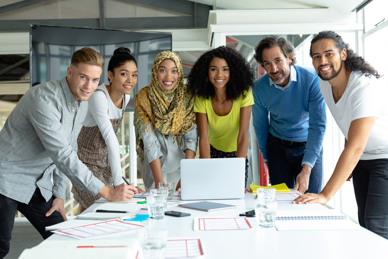 A group of employees are gathered around a notebook